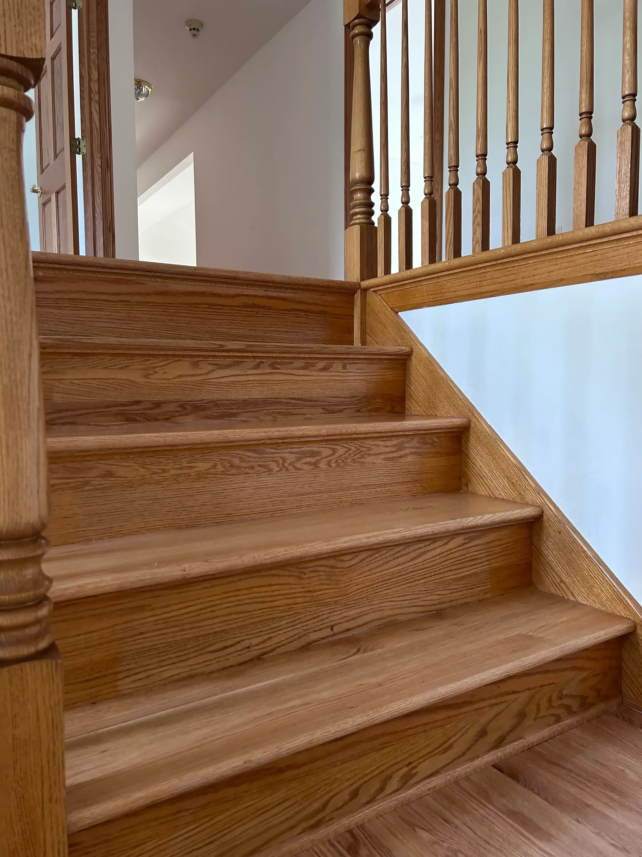 Solid oak staircase with turned balusters, wood handrail, and finished treads