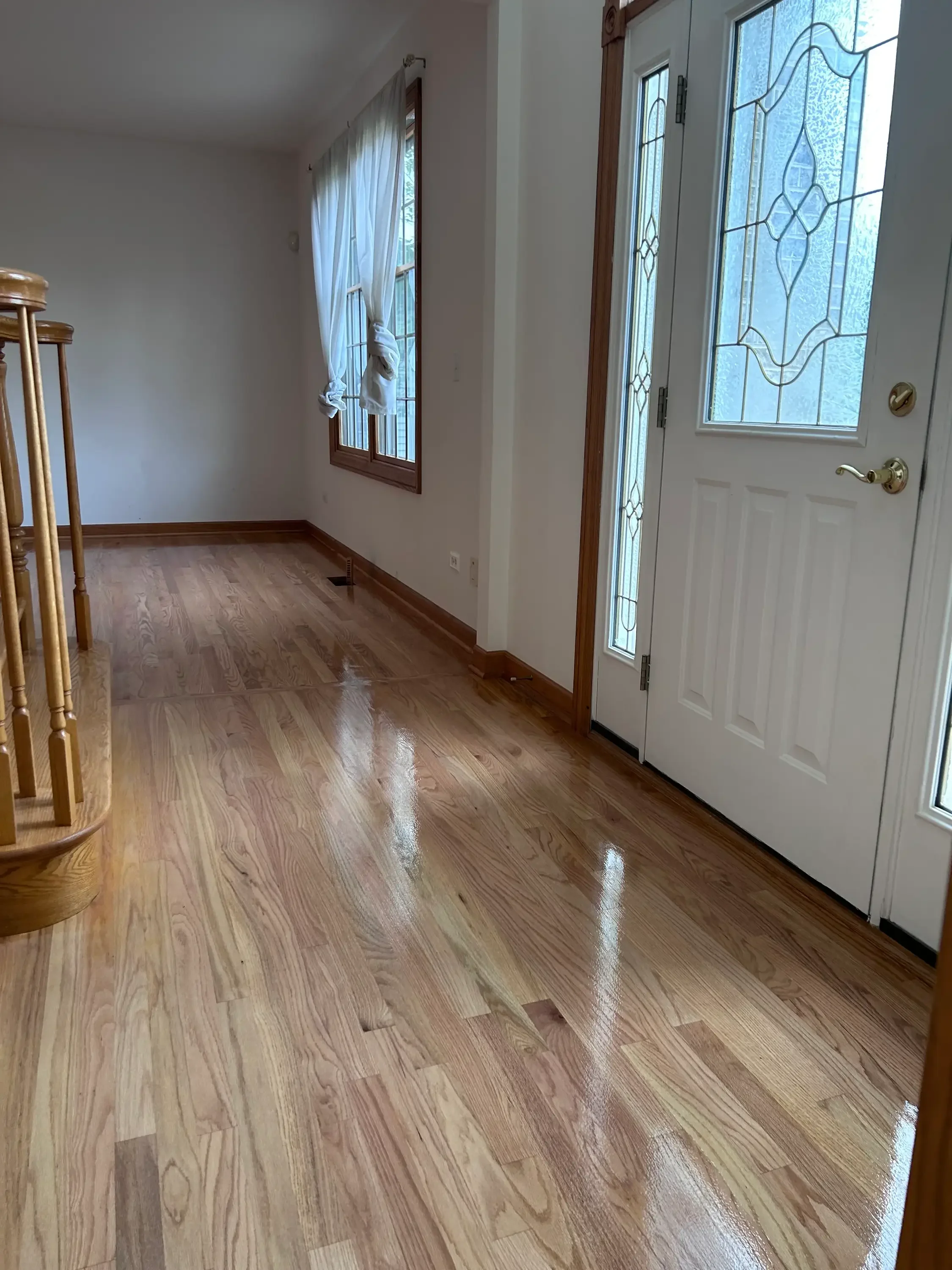Medium-tone hardwood flooring with stained wood trim and polished finish in entryway
