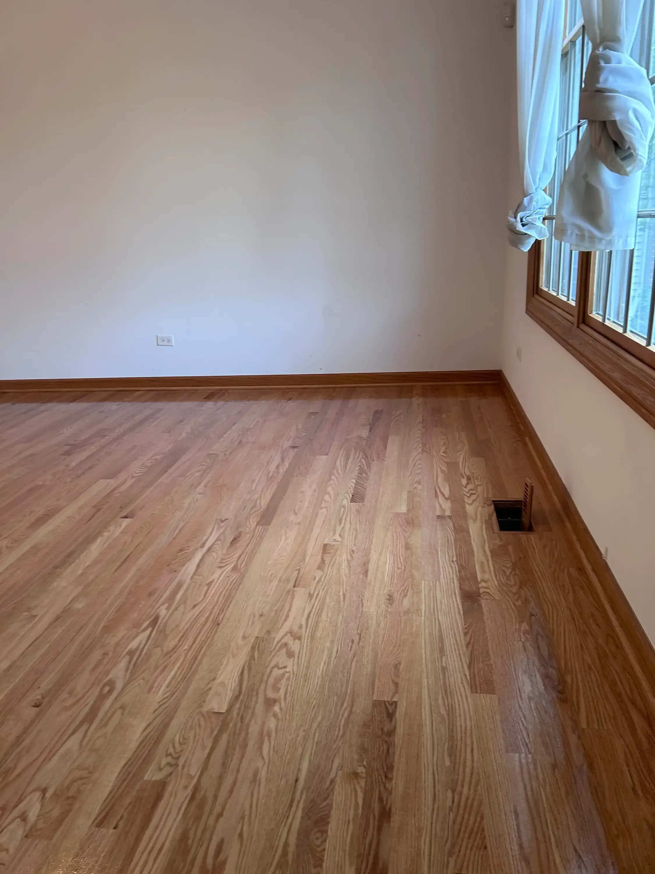 Newly installed solid oak hardwood flooring with matching baseboard trim in residential room
