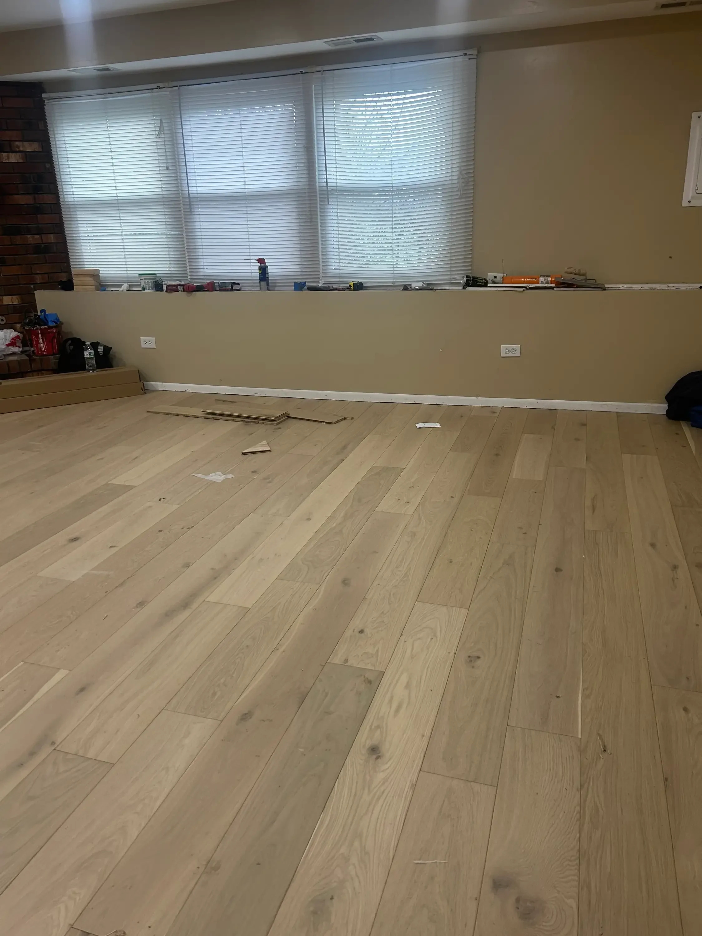 Light oak plank flooring installation with staggered random-width layout in residential room