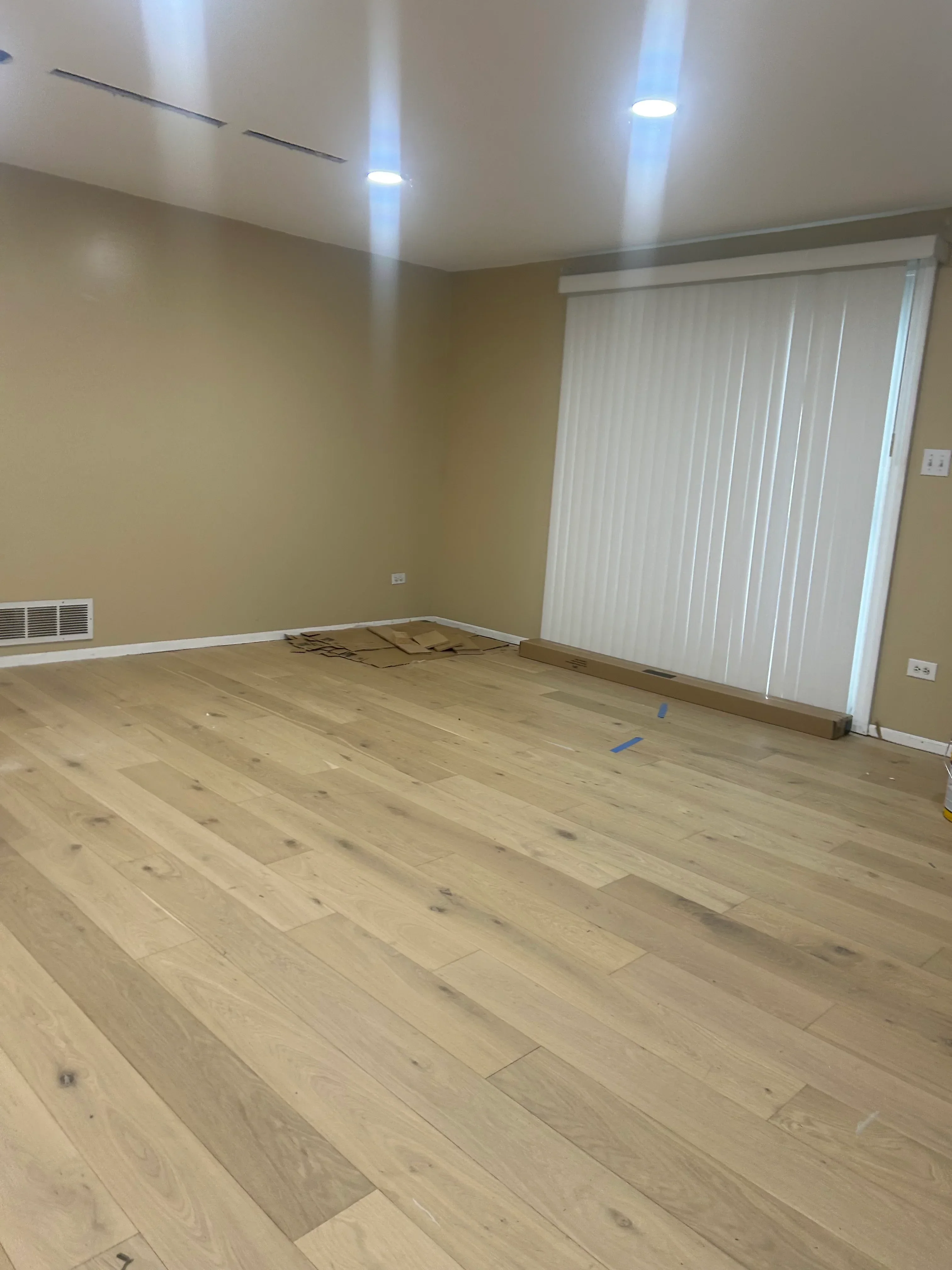 Light oak plank flooring installation in residential room with yellow walls and recessed lighting